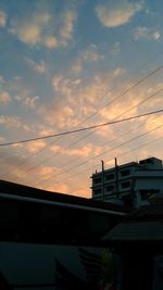 Power lines against sky during sunset