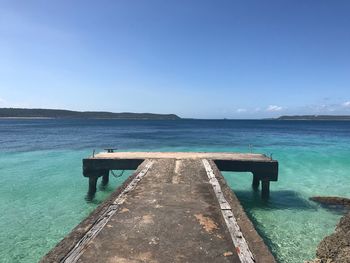 Pier over sea against clear blue sky