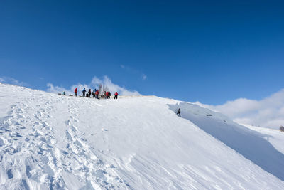 People on snowcapped mountain against sky
