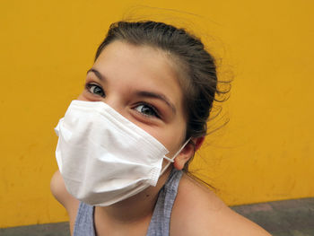 Portrait of teenage girl against yellow wall