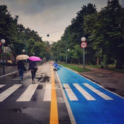 Rear view of people walking on road in rain