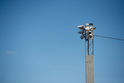 Low angle view of telephone pole against clear blue sky