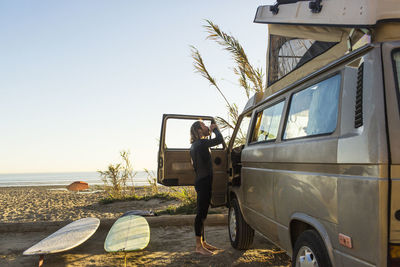 Side view of male surfer having drink outside mini van on san onofre state beach