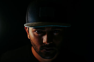 Close-up portrait of serious man wearing cap in darkroom