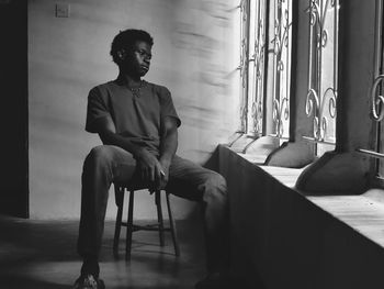 Young man sitting on a wooden chair as he thinks more about life.