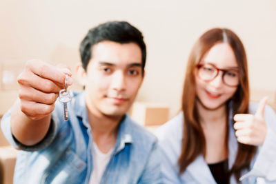 Portrait of young couple with key at home