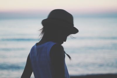 Woman looking at sea against sky during sunset