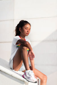 Girl looking away while sitting on wall