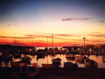 Chairs and table by sea against sky at sunset