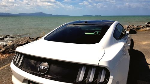 Vintage car on land by sea against sky