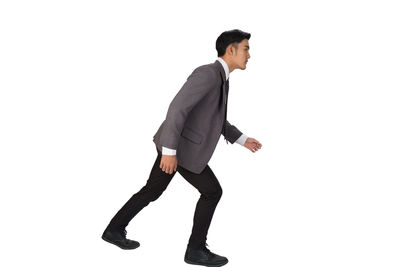 Side view of young man standing against white background