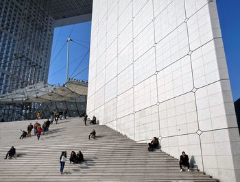 People walking on modern office building against clear sky