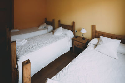 View of a triple room with three wooden beds in a spanish village hotel.