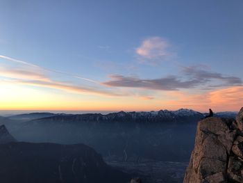 Man looking at view of rocks against sky during sunset