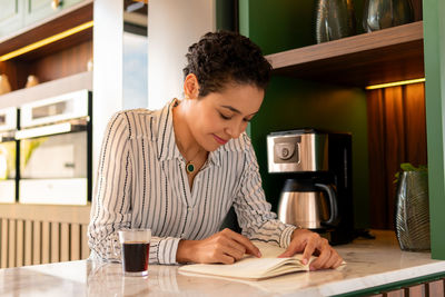 Young woman using phone while sitting on table