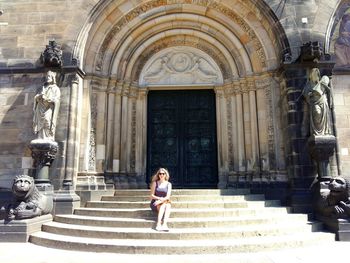 Full length of woman sitting on steps of cathedral