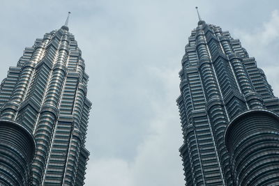 Low angle view of petronas towers against cloudy sky