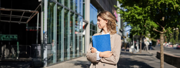 Full length of young woman standing in city