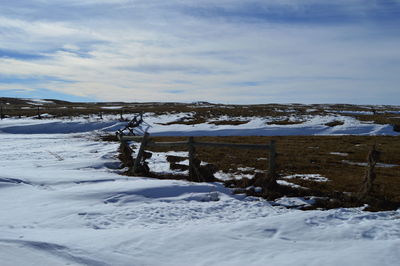 Scenic view of snow covered field against cloudy sky