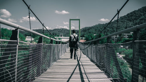 Rear view of man standing on footbridge