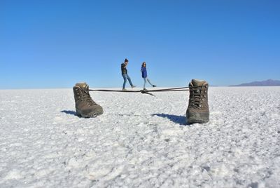 Optical illusion of couple walking on shoelaces at salt flat