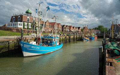 Boats moored at harbor against cloudy sky