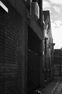 Brick wall by building in city against sky