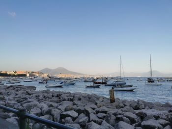 Sailboats moored on sea against clear sky
