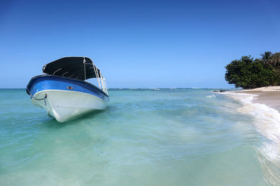 Boat in sea against clear blue sky