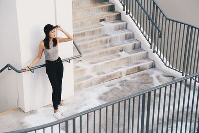 Full length of young woman standing by railing on staircase