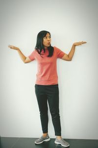 Full length portrait of woman standing against wall