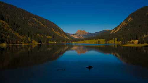 Scenic view of lake and mountains against blue sky