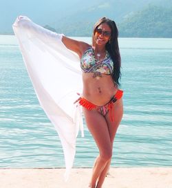 Portrait of woman in bikini standing at beach