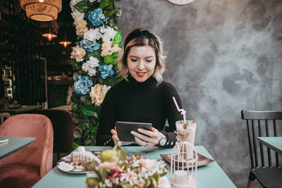 Young woman using smart phone in restaurant