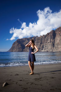 Full length of woman standing at beach against sky