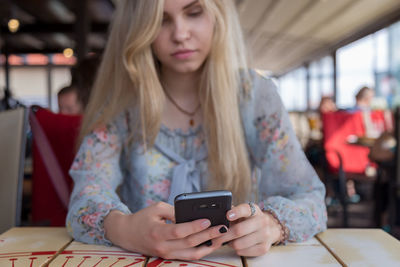 Young woman using mobile phone at restaurant