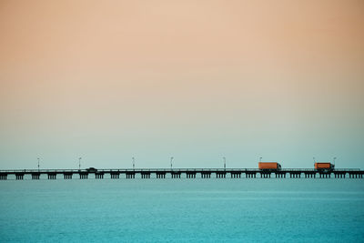 Pier over sea against clear sky during sunset