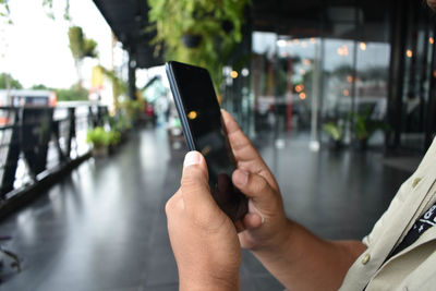 Midsection of man using mobile phone in city