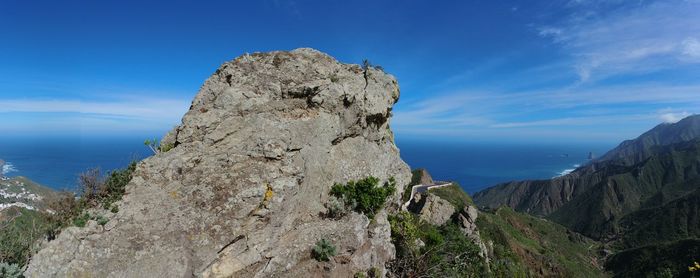 Rock formation by sea against blue sky