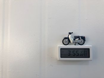 Toy motorcycle over clock hanging on wall