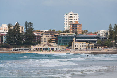 Buildings by sea against sky in city