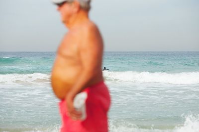 Rear view of man standing on beach against clear sky