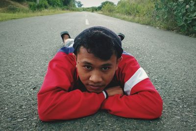 Close-up portrait of young man lying on road