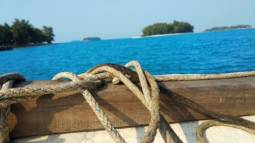 Close-up of rope tied on bollard by sea against sky