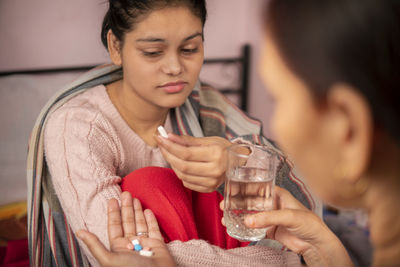 Close-up of young woman drinking juice at home