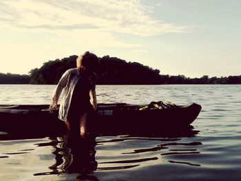 Woman standing by lake against sky