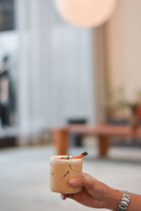 Close-up of hand holding drink on table