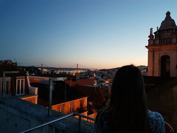 Rear view of woman standing in city against clear sky