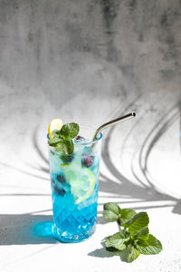 Curacao blue cocktail with fresh blueberries and lemon wedges, garnished with mint 