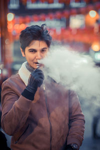 Portrait of young man smoking cigarette in city